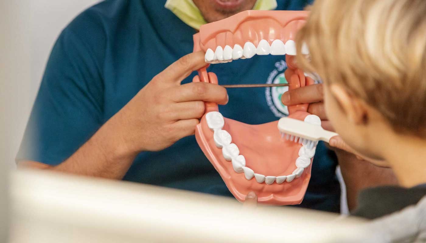 Dr. Heinz showing young patient how to brush the teeth